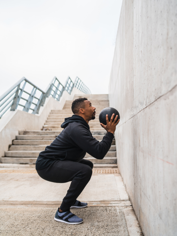 Athletic man doing wall ball exercise