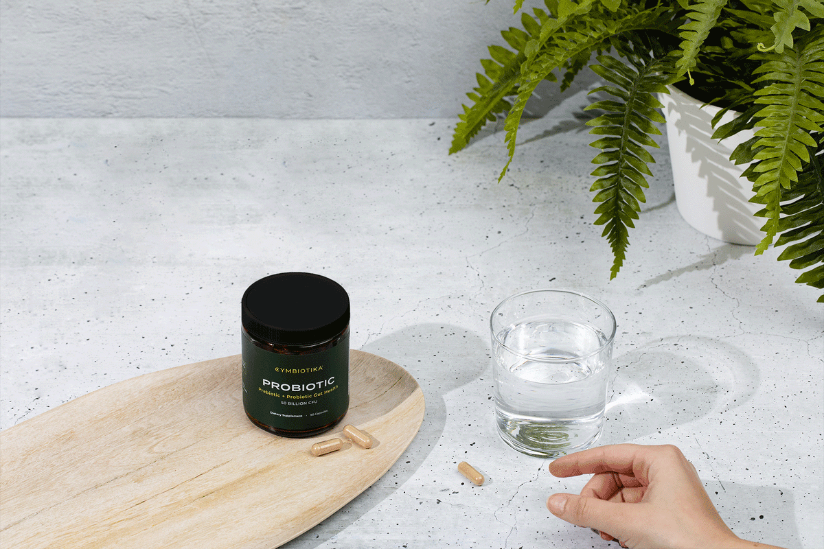Hand Grabbing Probiotic Pills Near Glass of Water Gif